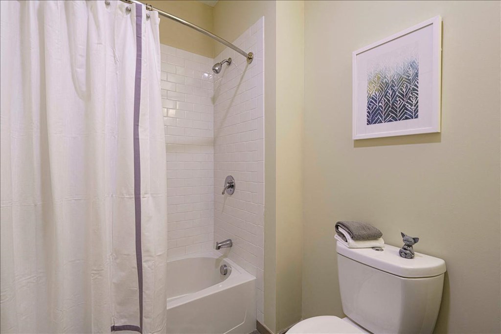 A white toilet sits next to a white bathtub in a bathroom at Axis at Lakeshore Apartments, Bridgewater, MA
