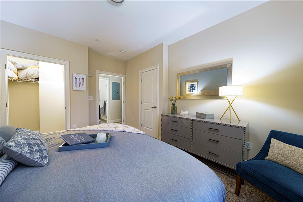 A bedroom with a bed, dresser, and mirror at Axis at Lakeshore Apartments, Bridgewater, Massachusetts, 02324