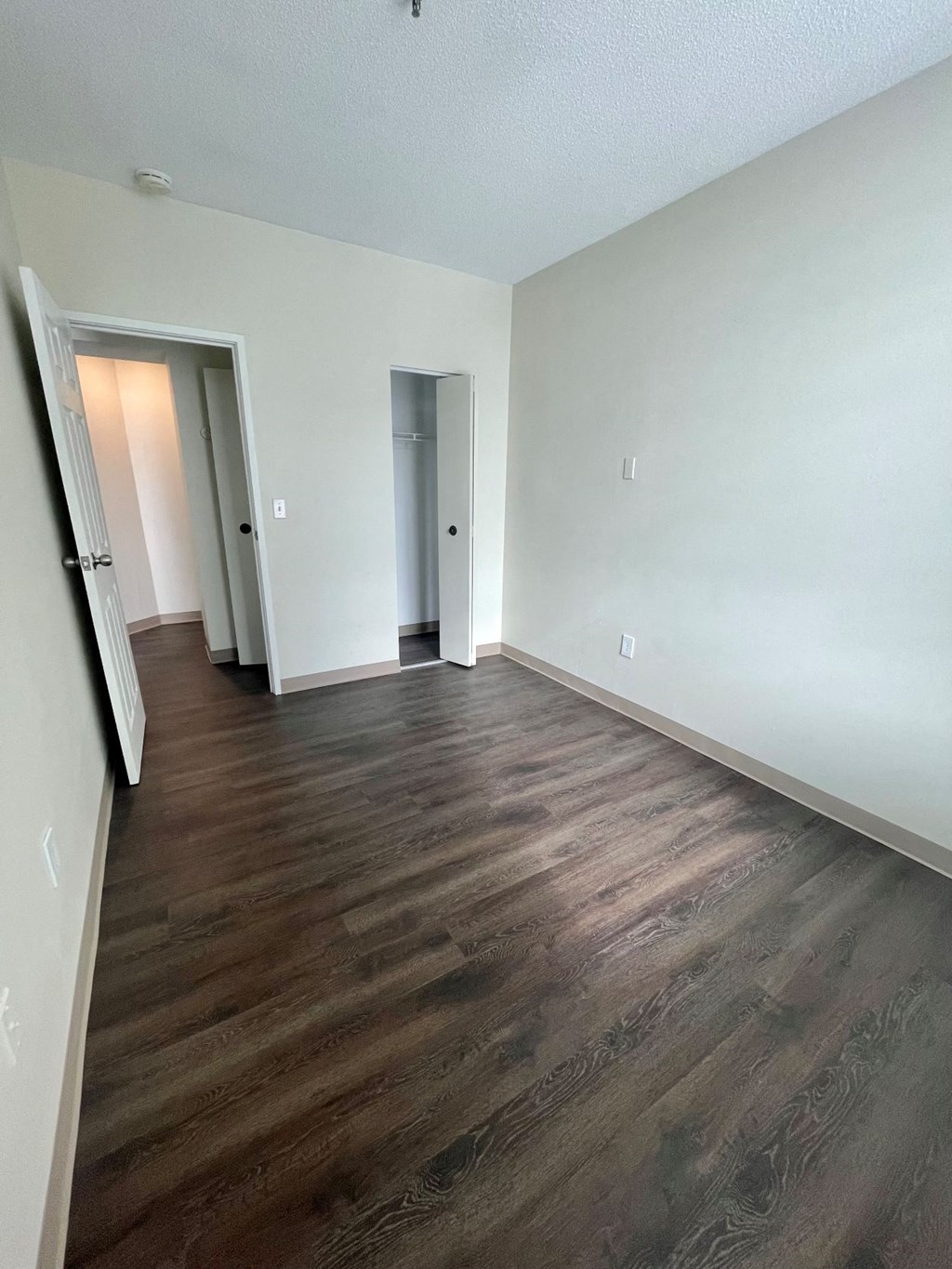 A room with wood flooring and two doors.