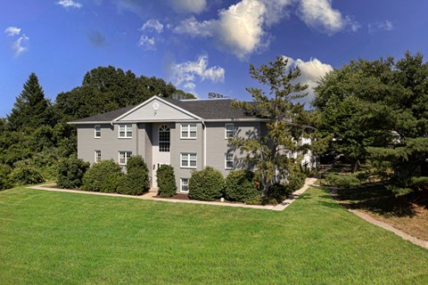 a large gray house with a lawn and trees