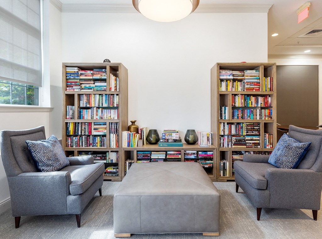 two chairs and a table in a library with bookshelves