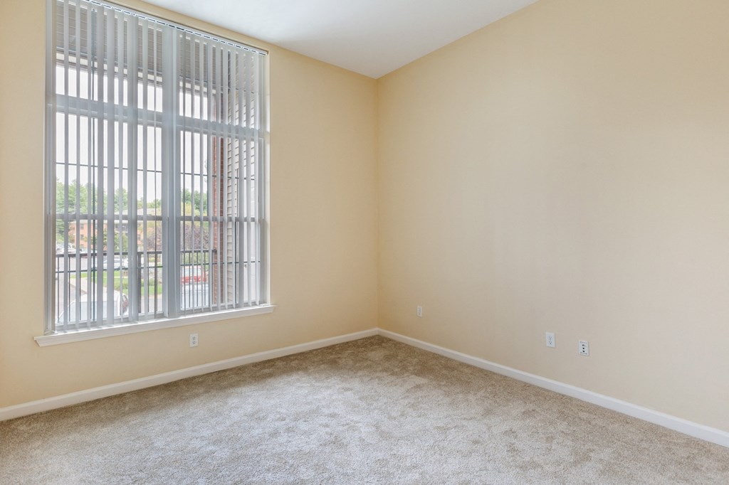 an empty living room with a large window and carpet