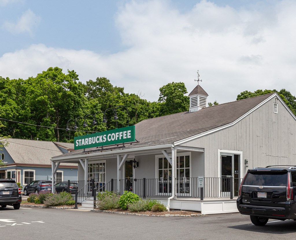 the front of a white building with a green sign that reads standards coffee