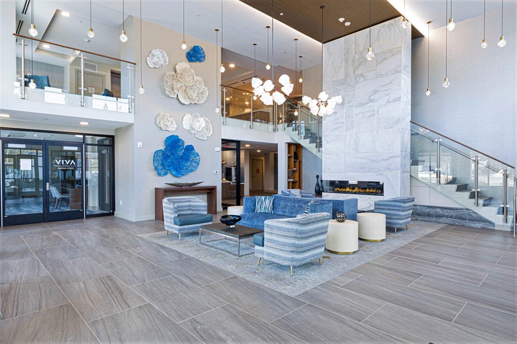 a lobby with a blue couch and chairs and a fireplace