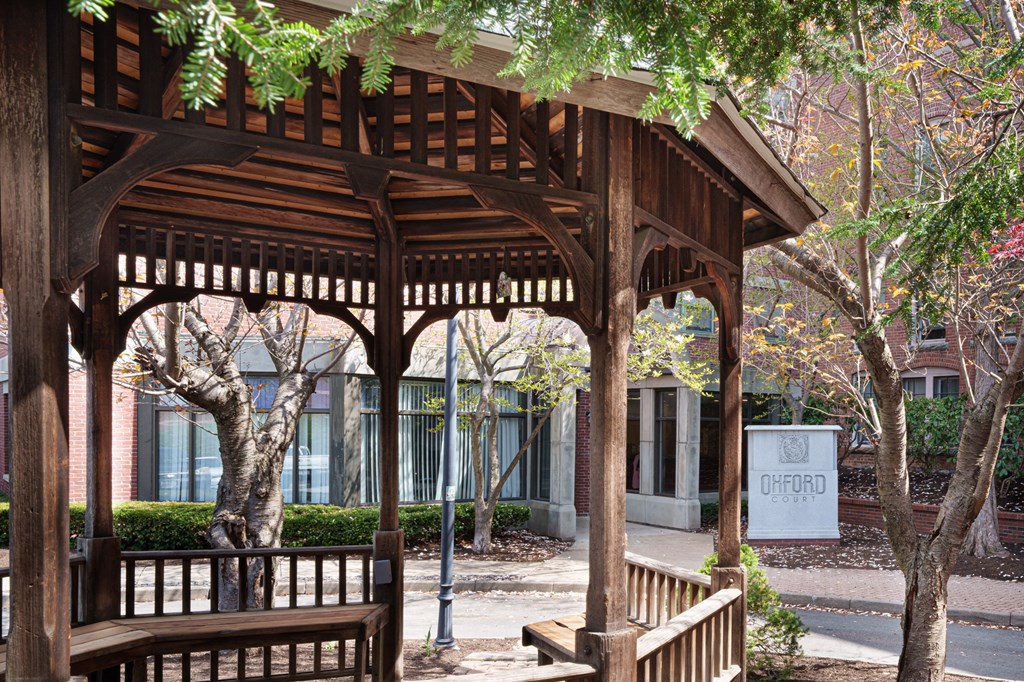 a wooden pavilion with benches in front of a building