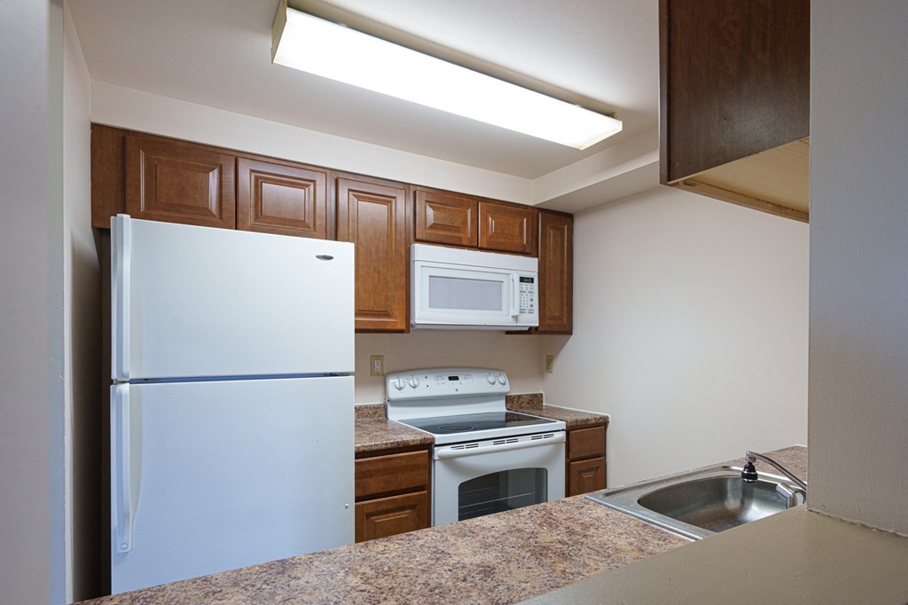 a kitchen with white appliances and wooden cabinets and granite counter tops