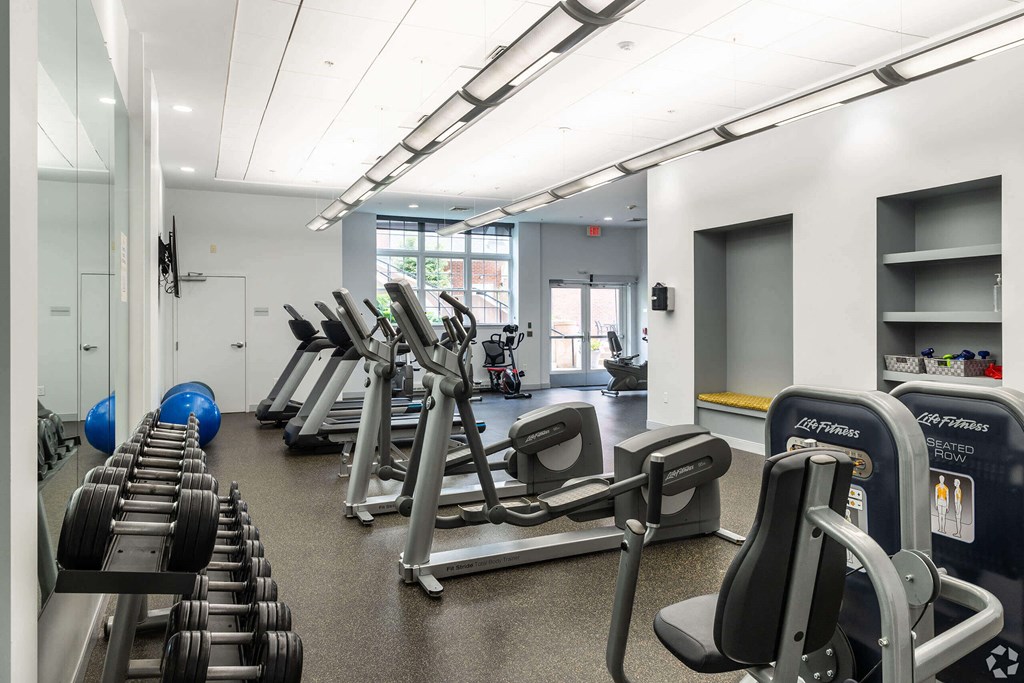 a gym with cardio equipment and weights on the floor