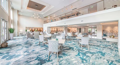 A spacious dining area with a carpeted floor and white chairs.