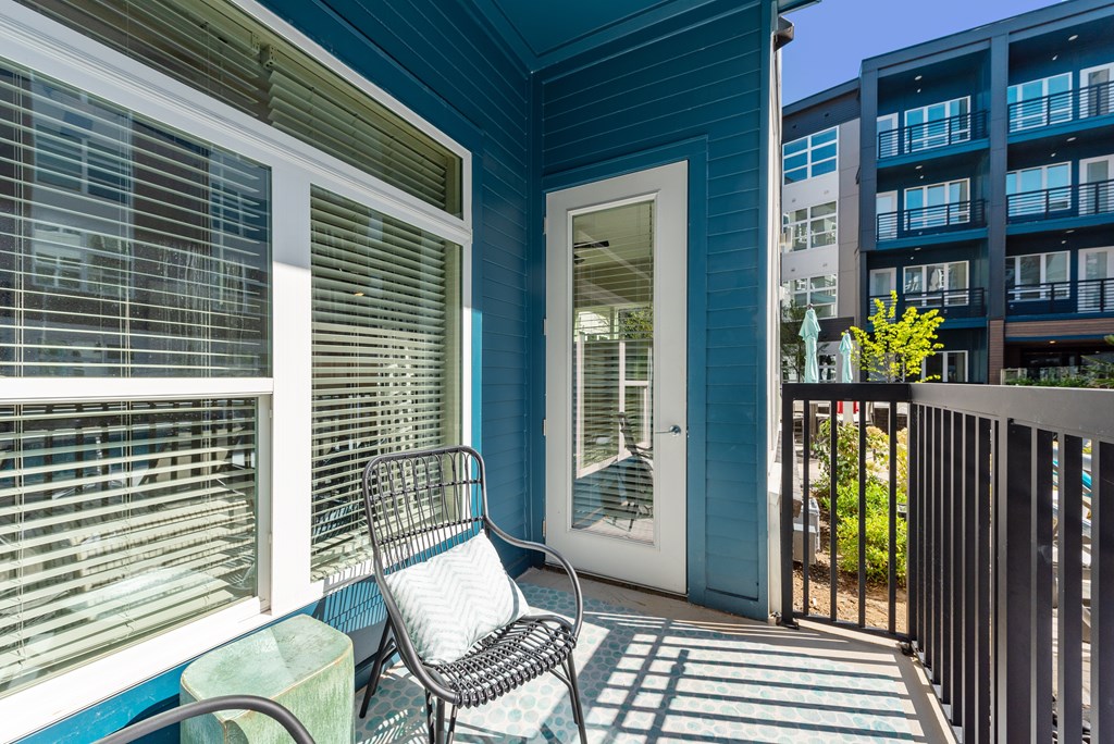A chair sits on a porch with a blue door and window.