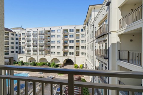 View from a private balcony over the courtyard, with the pool below and balconies across the facing building wing.