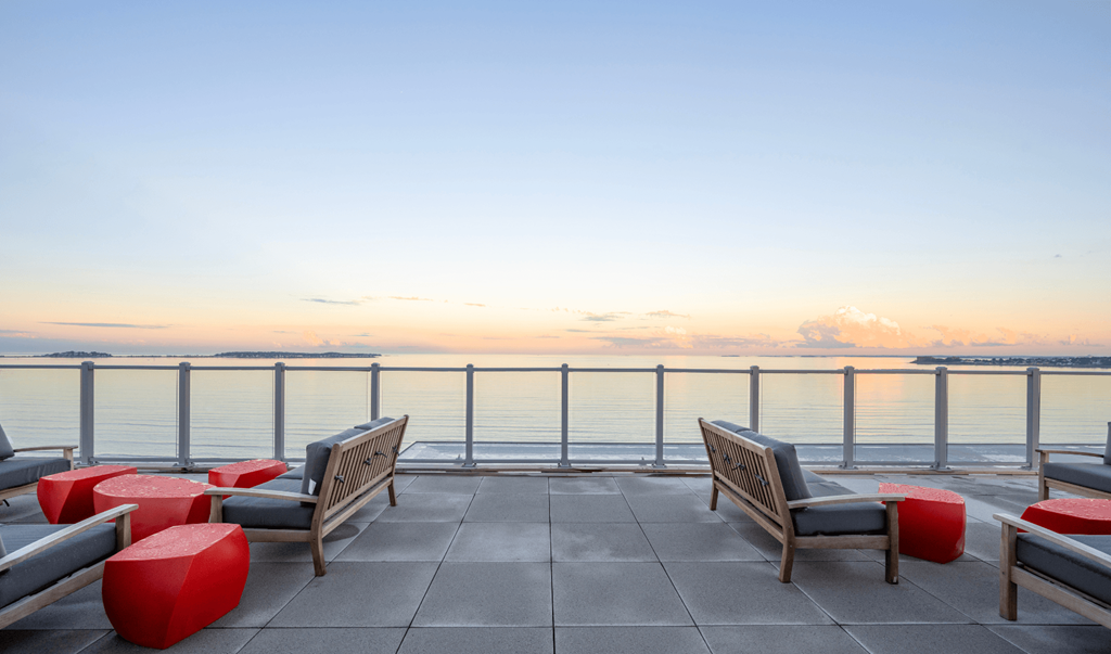 A sunset view from a rooftop with a bench and a table.