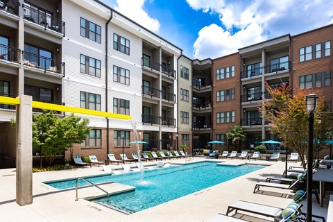 Courtyard pool at 675 N. Highland with fountain jets, a spa, lounge chairs, and teal umbrellas along the deck.