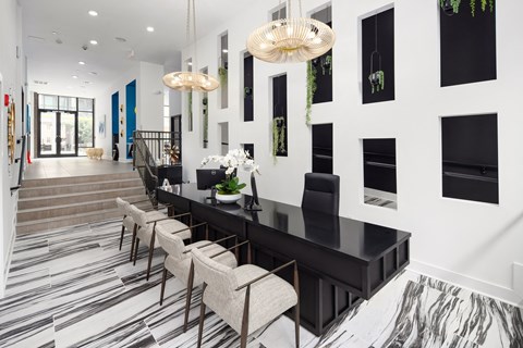 Leasing office with a long black desk, upholstered chairs, woven ring pendants, and planted niches along the wall.