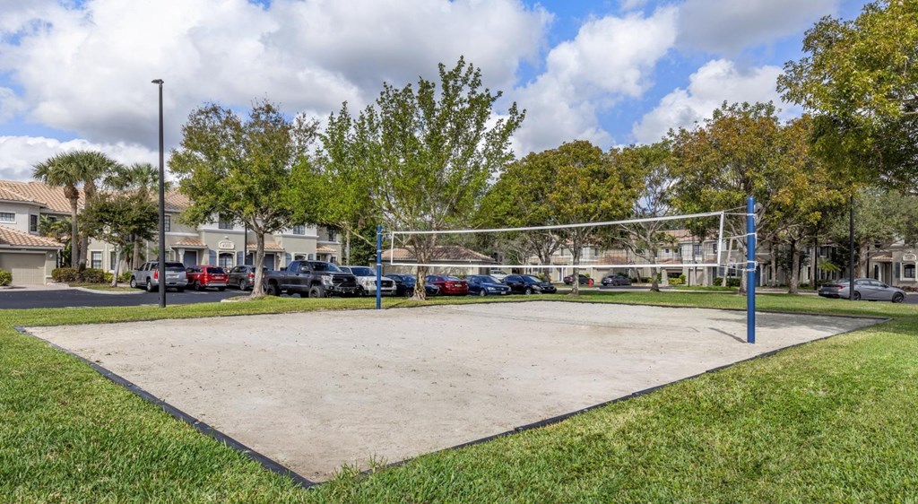 A volleyball net is set up in the middle of a sandy court.