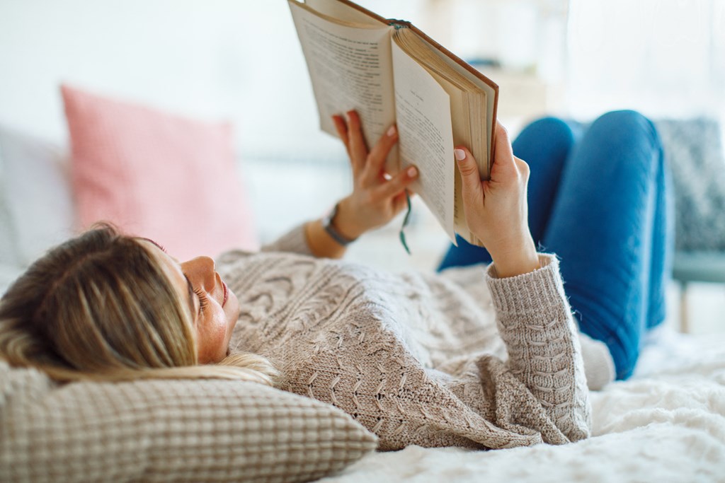 a woman laying on a bed reading a book