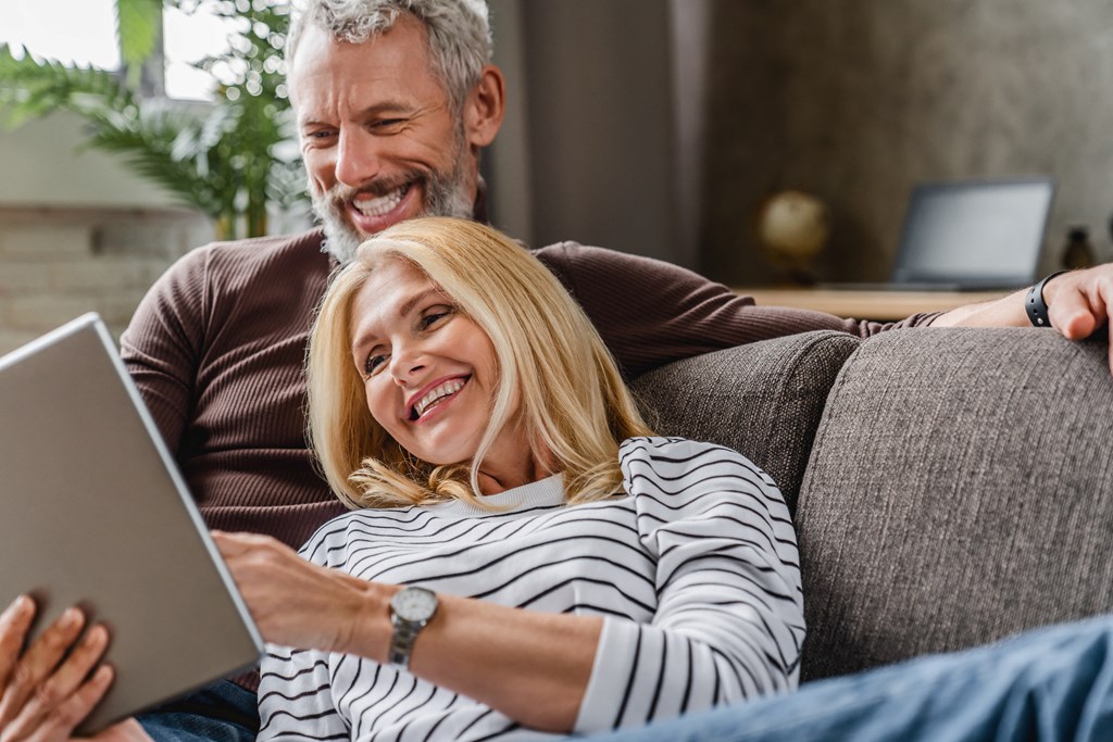 a couple sitting on a couch using a laptop computer
