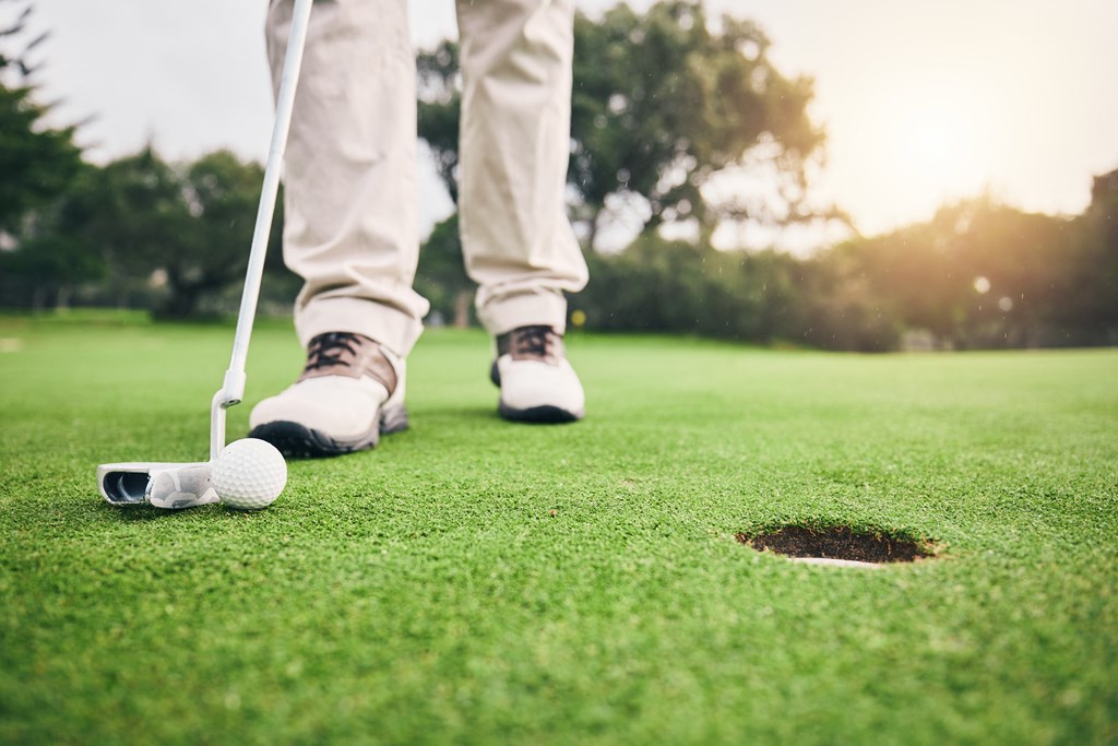 a golfer standing next to a hole on the golf course