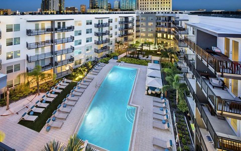 Aerial Poolside Scene with City Skyline Views and Illuminated Courtyard