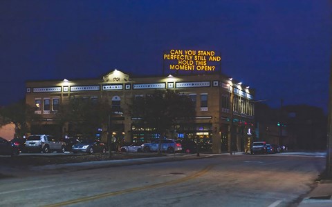 Evening View of Brick Building with Artistic Rooftop Message and Street Lighting