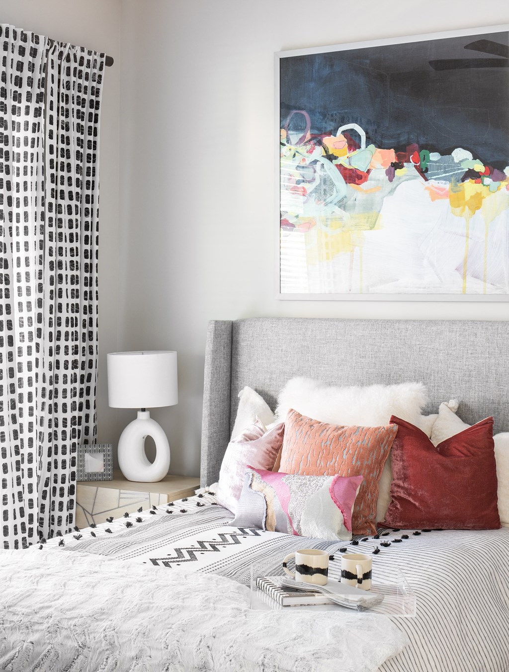 a bedroom with a bed and pillows and a painting on the wall