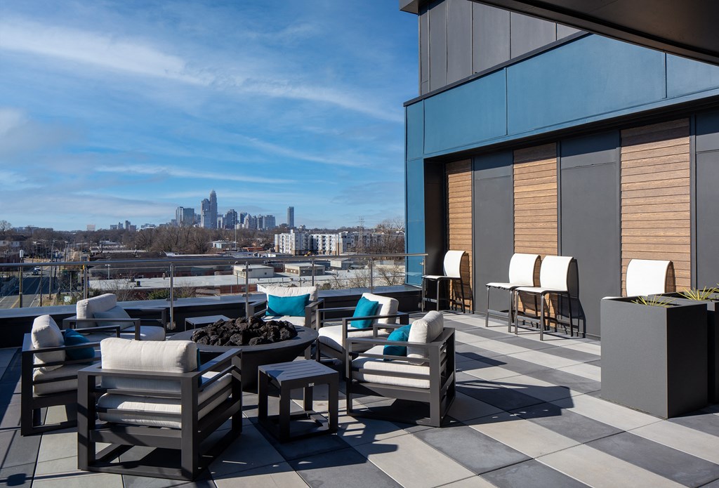 a rooftop patio with chairs and tables and a view of the city
