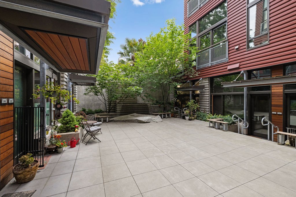 A patio with a table and chairs is surrounded by buildings.