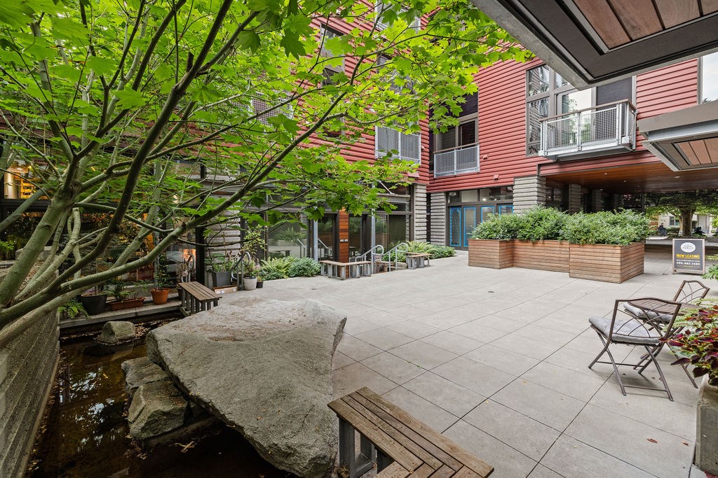 A patio with a bench and a tree in front of a building.