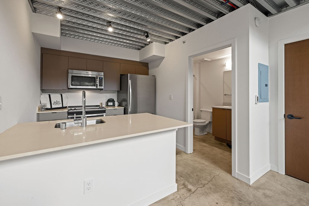A kitchen with white countertops and a brown cabinet.