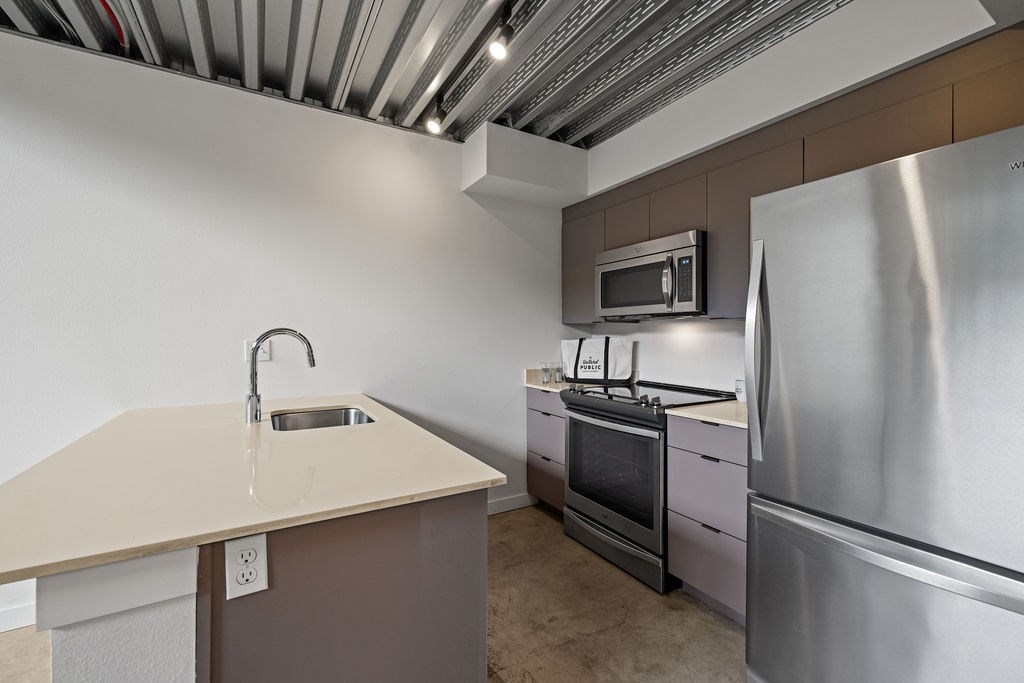 A kitchen with a stainless steel refrigerator, microwave, and oven.