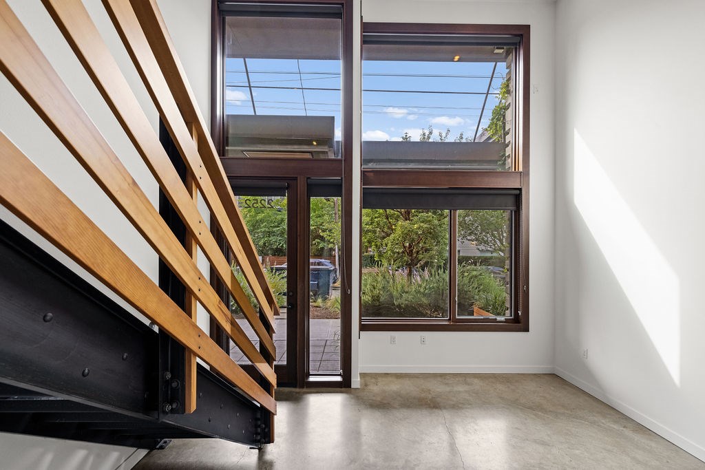 A room with a wooden staircase and a glass door leading to a balcony.