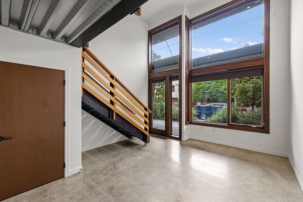 A room with a brown door and a staircase leading to a balcony.
