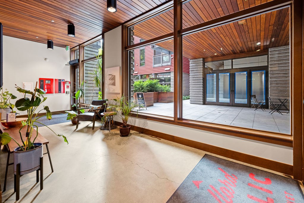 A room with a wooden ceiling and floor, and a large window with a view of the outside.