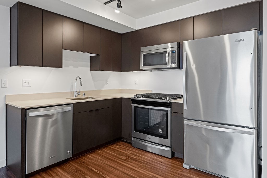 A modern kitchen with stainless steel appliances and wooden floors.