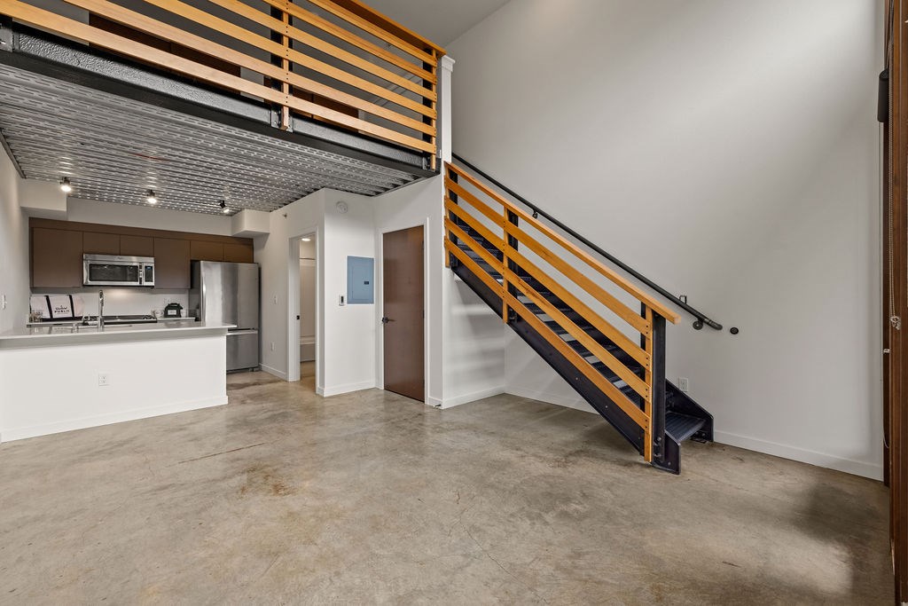A room with a staircase and a kitchen area.