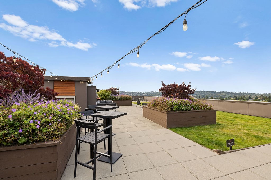 A patio with a table and chairs overlooking a grassy area.