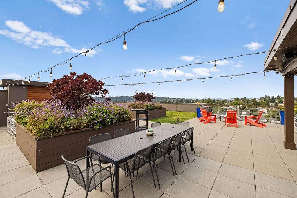 A patio with a table, chairs, and string lights.