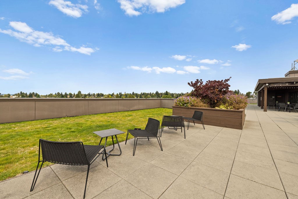 A patio with a table and chairs overlooking a grassy field.