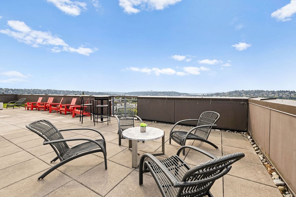 A patio with black metal chairs and tables overlooks a cityscape.
