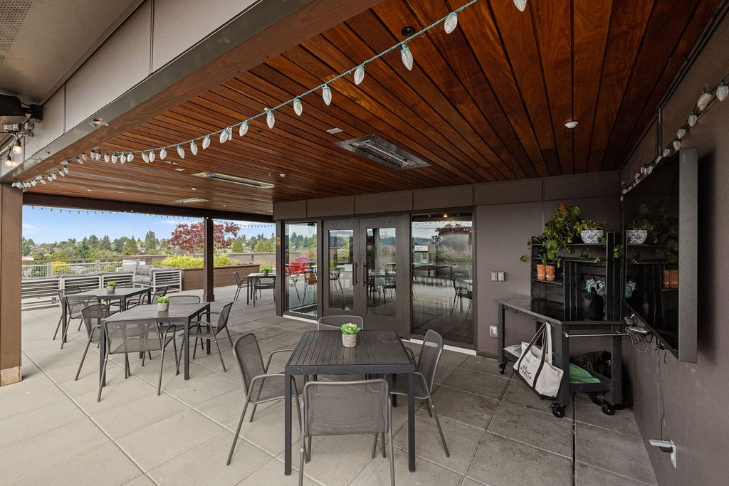 A patio with tables and chairs and a wooden ceiling.