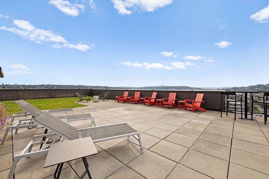 A patio with tables and chairs overlooking a grassy area.