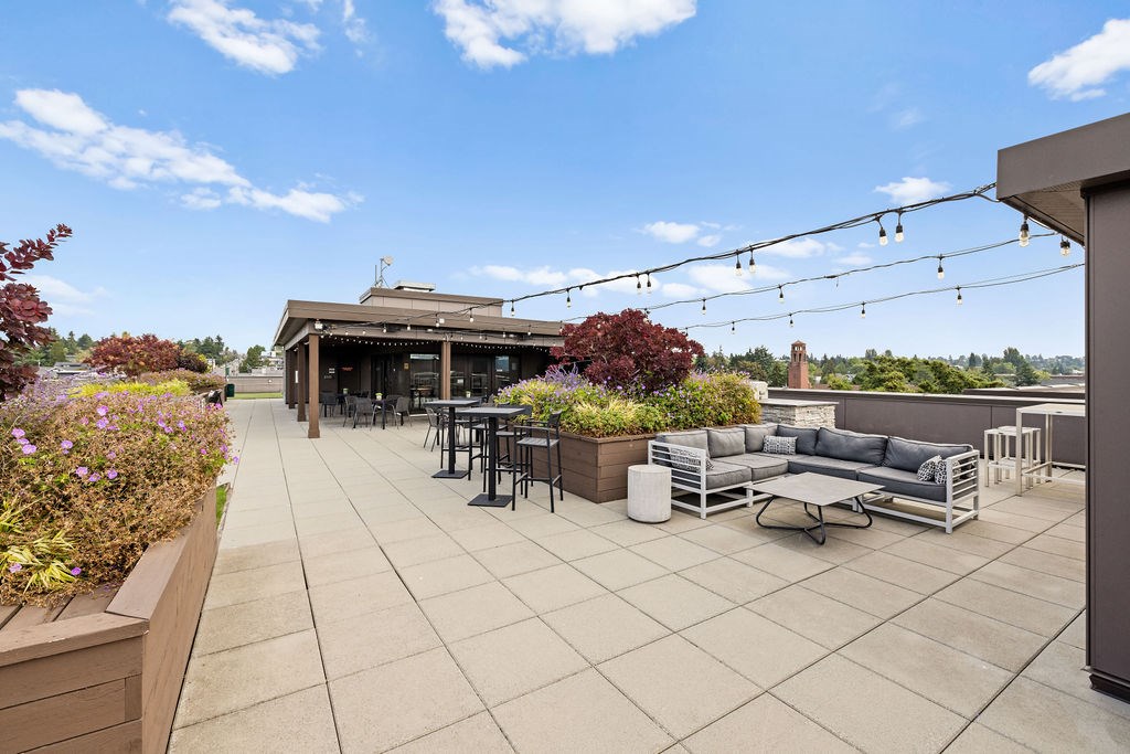 A patio with a table and chairs is surrounded by plants.