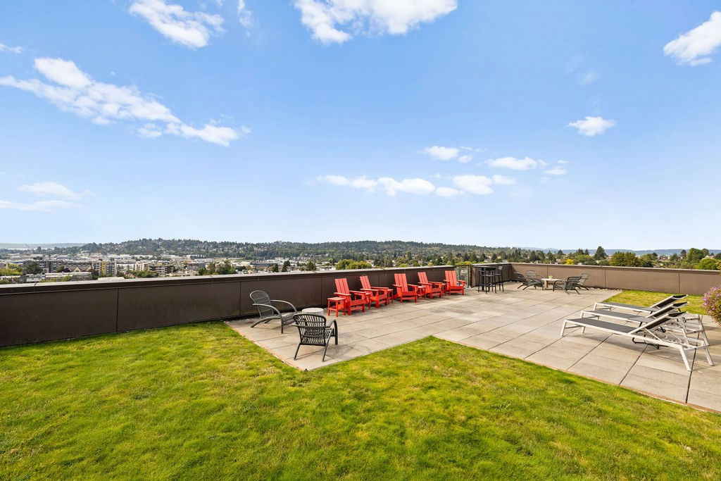A patio with red chairs and a table is set up on a grassy area.
