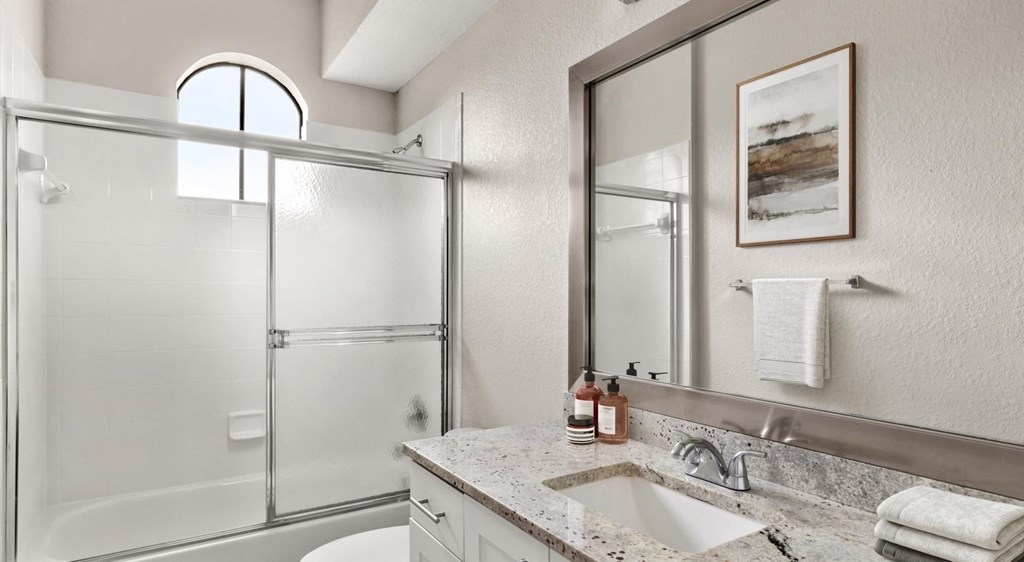 A bathroom with a white sink and a glass shower stall.
