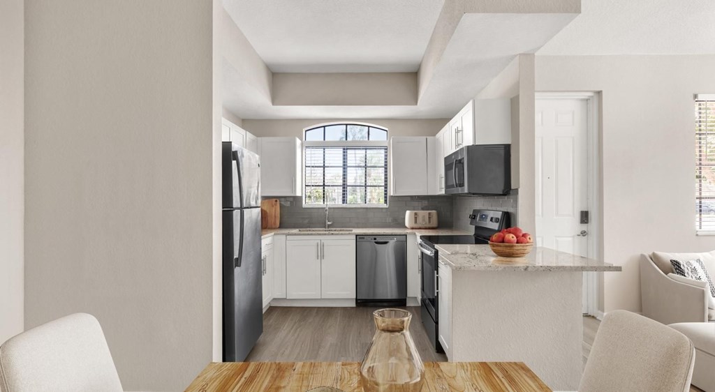 A modern kitchen with white cabinets and a wooden table.