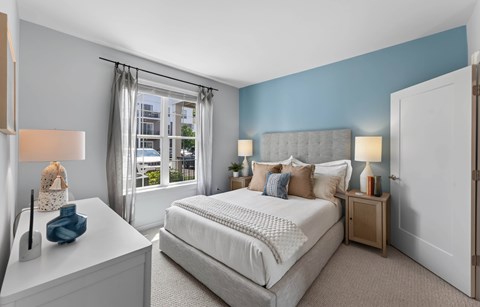 A bedroom with a large bed and a window with curtains.