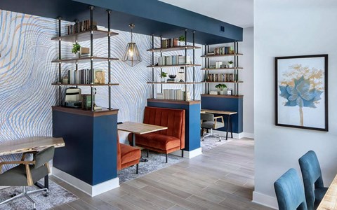 Business center with individual workstations, task chairs, a velvet booth, open shelving, and a patterned accent wall.