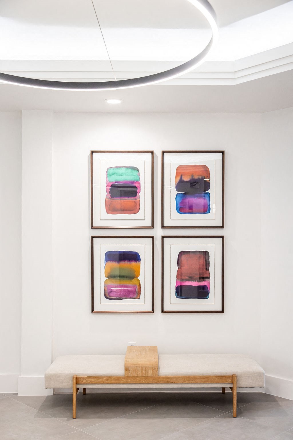 a seating area with four paintings on the wall and a bench