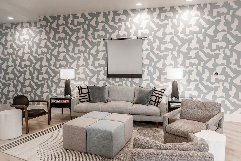 a living room with a couch and chairs and a wall of wallpaper