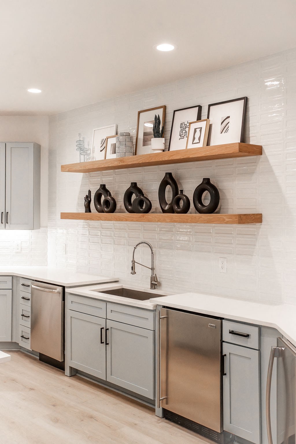 a white kitchen with stainless steel appliances and wooden shelves