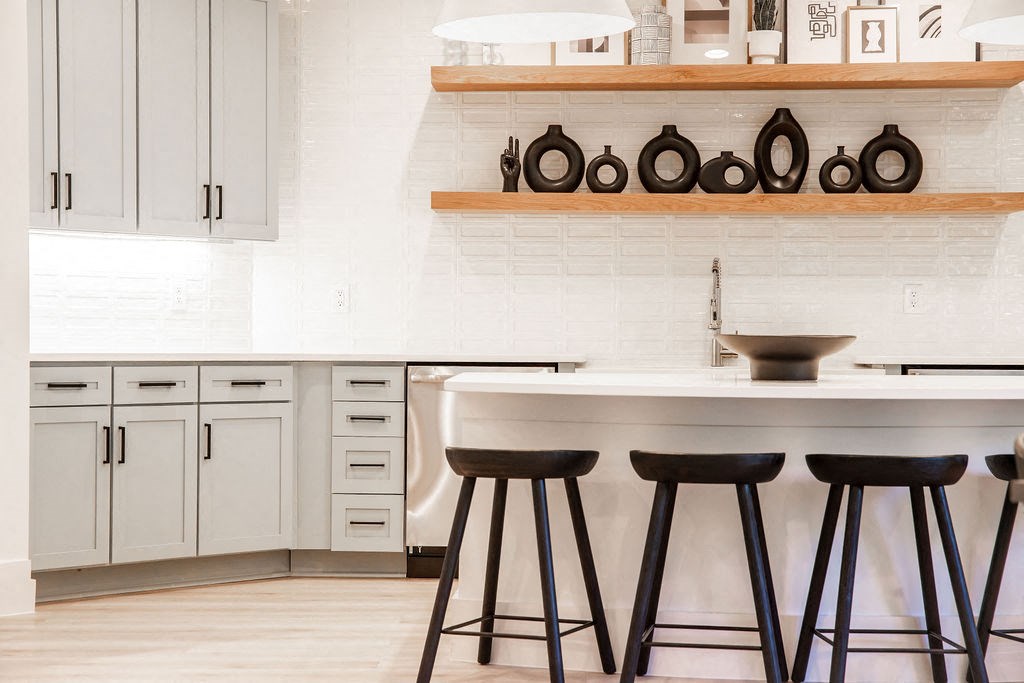 a kitchen with white cabinets and a counter with black stools